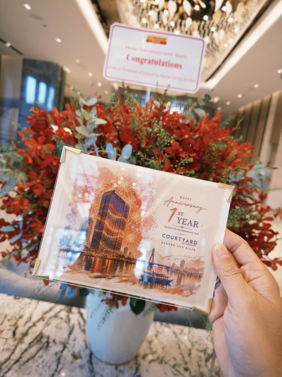 A gold-cornered Dó paper commemorative card held in hand